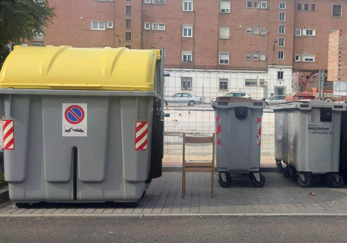 Una silla abandonada entre contenedores en la calle Amor de Dios.