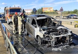 Los bomberos, junto al coche calcinado.