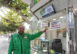 Rafael Cítores Pobes señala el cartel que anuncia el premio, junto a su quiosco frente a Lecràc.