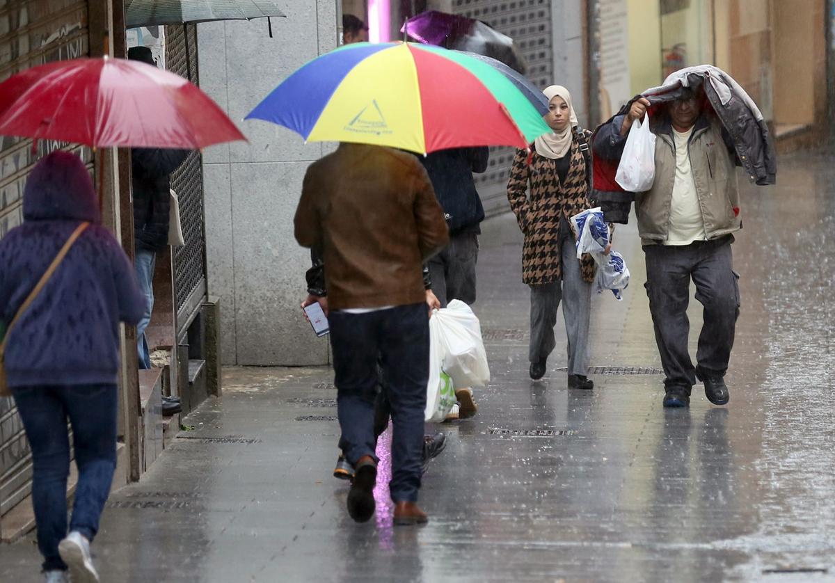 Varias personas caminan por la calle San Francisco en pleno diluvio.