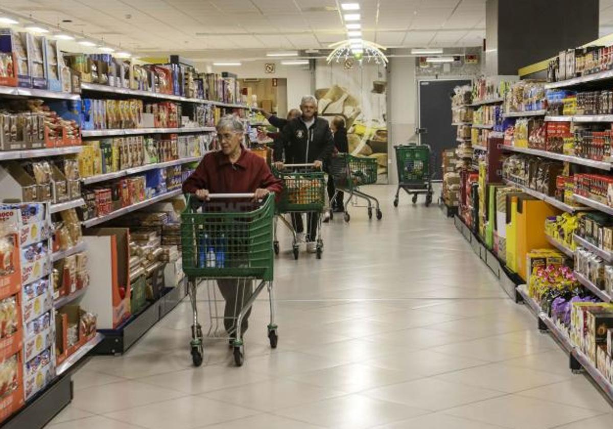 Varias personas hacen la compra en el interior de un supermercado.