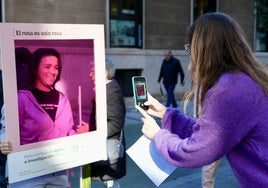 Una mujer posa con el marco rosa de la campaña para reclamar investigación contra el cáncer de mama.