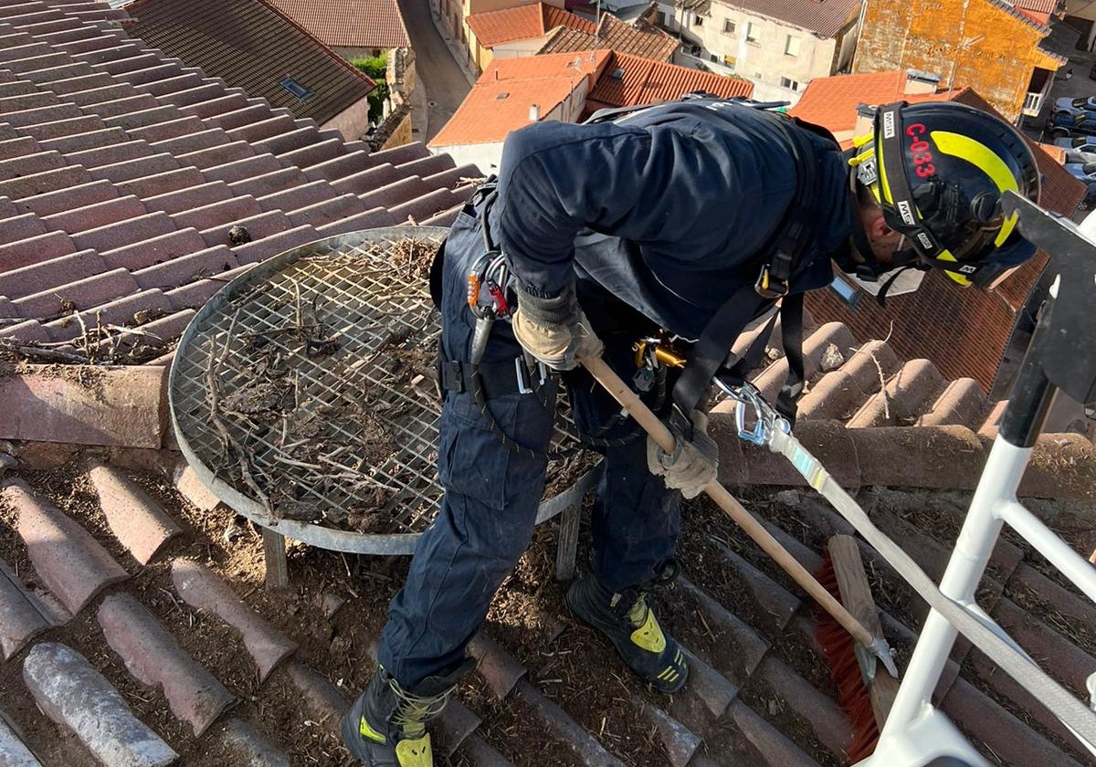 Uno de los bomberos terminando de retirar el nido de la plataforma de la torre de la iglesia de San Juan Bautista.