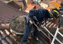 Uno de los bomberos terminando de retirar el nido de la plataforma de la torre de la iglesia de San Juan Bautista.