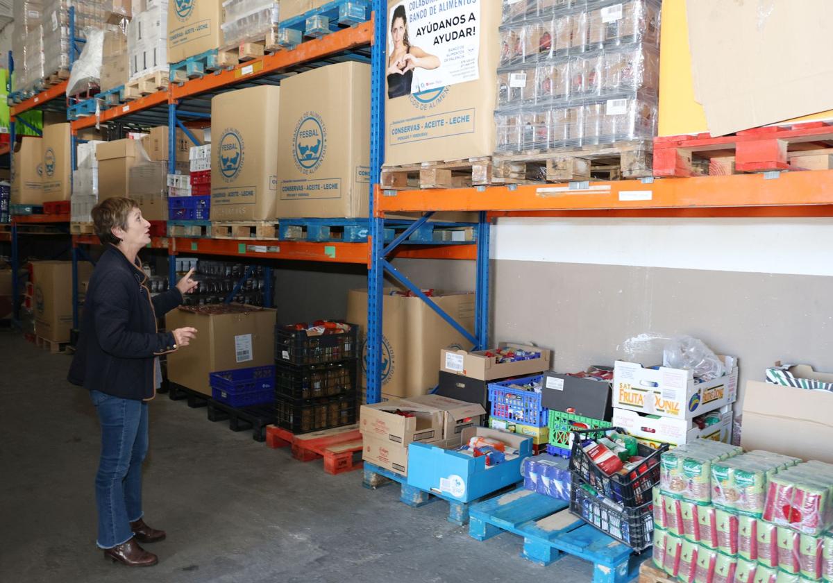 La secretaria del Banco de Alimentos, Rosa Ortega, ante los palés de comida en las instalaciones de la organización.