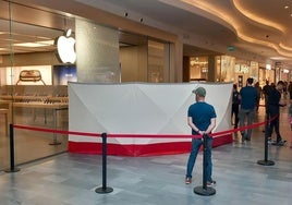 Vigilantes y personal de Apple custodian la entrada, con la luna rota, a la entrada de la tienda.