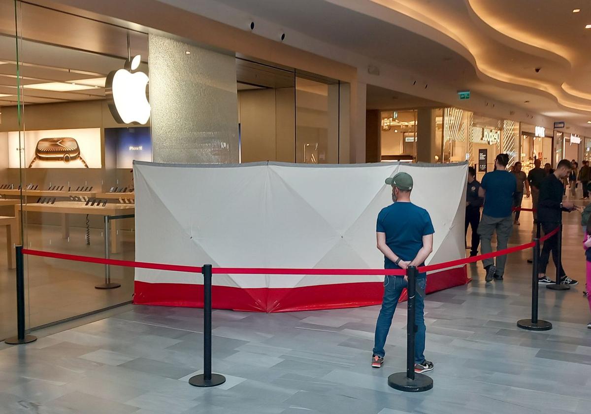 Vigilantes y personal de Apple custodian la entrada, con la luna rota, a la entrada de la tienda.