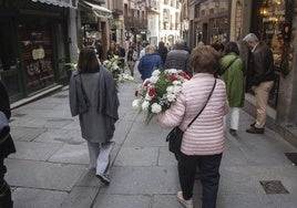 Dos mujeres abrigadas portan arreglos florales recién comprados.