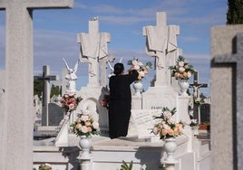 Una mujer coloca varias flores en una de las sepulturas del cementerio municipal de El Carmen.