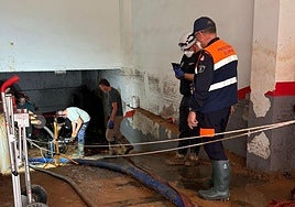Miembros de Protección Civil El Espinar vacían de agua un garaje.