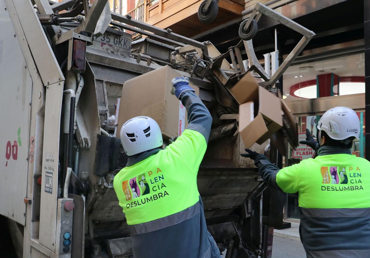 Dos trabajadores recogen cajas y residuos de la zona comercial de la Calle Mayor.