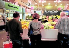 Varios clientes en un puesto de frutas del Mercado del Val.