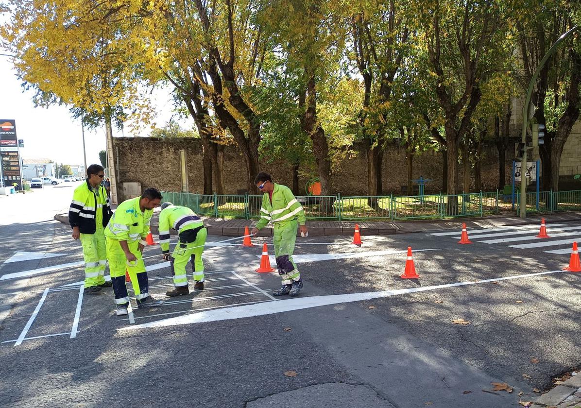 Unos operarios trabajan en reforzar la pintura en una calle de la villa segoviana de Cuéllar.