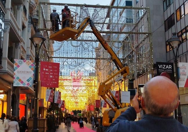 Un hombre fotografía las pruebas de luz de los arcos de la calle Santiago, en los que aún trabajan los operarios.