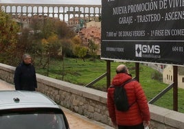 Un hombre observa un cartel colocado junto a los terrenos en los que se construirá la promoción de viviendas.