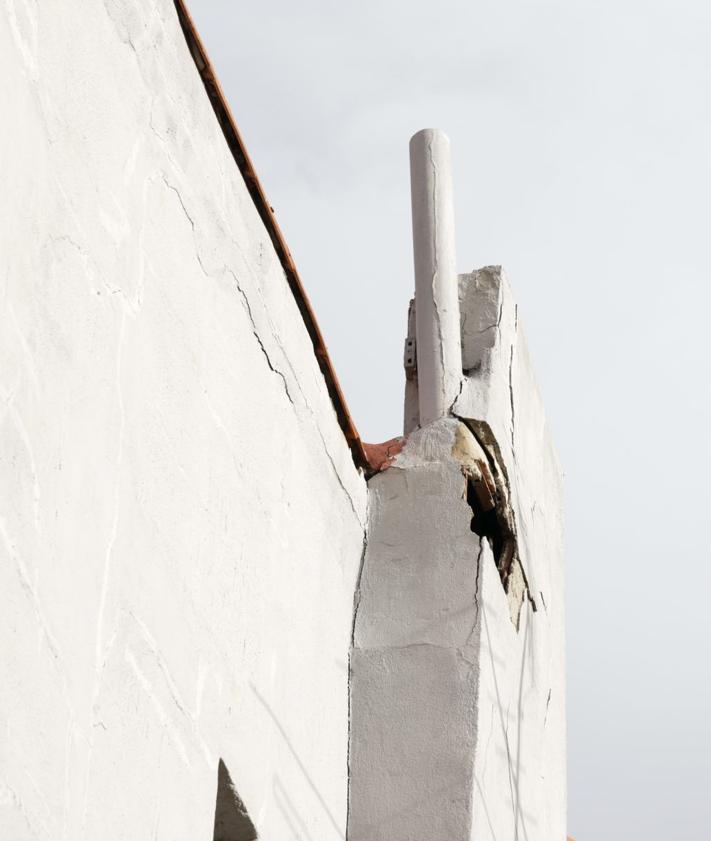 Imagen secundaria 2 - Una familia camina por el acceso peatonal junto al edifcio. La antena decolgada sobre el tejado y parte de la chimenea que se desprendió el 3 de noviembre.