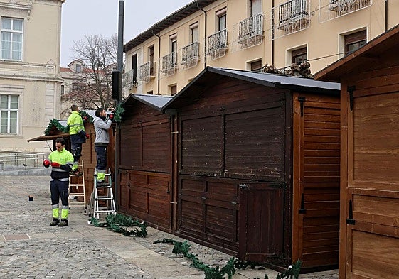 Un grupo de operarios coloca adornos en las casetas instaladas en la Plaza Mayor.