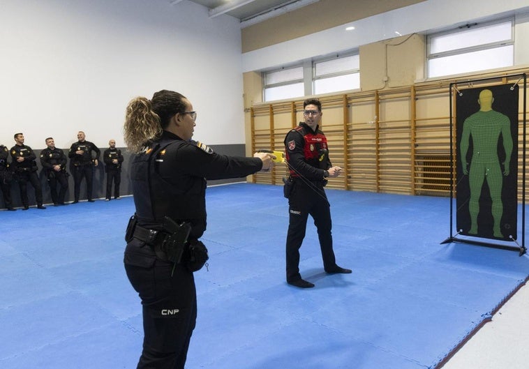 Una policía acciona la Taser ante la atenta mirada del instructor del curso.