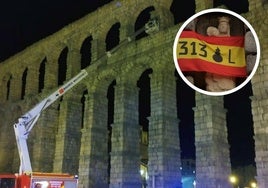 Los bomberos despliegan la escala para colocar la bandera, en el círculo, la insignia ya puesta en la Virgen del Acueducto de Segovia.