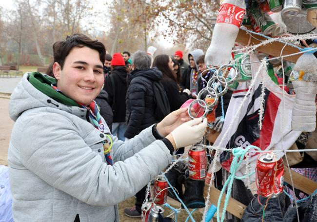 Un joven scout coloca un adorno en el árbol reivindicativo de la playa de Las Moreras.