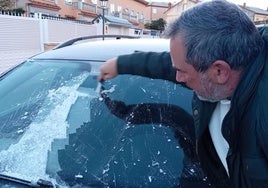 Un hombre raspa el hielo de la luna de su coche este lunes.