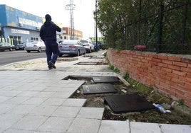 Un trabajador camina por el cruce de la avenida de El Norte de Castilla con Forja entre registros sin rematar, arena y agujeros cubiertos con palés.