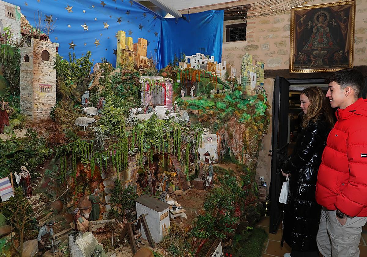 Dos jóvenes observando uno de los belenes durante la inauguración de la muestra en el monasterio de las Clarisas.