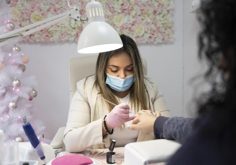 Ángela Cuñado en Adore Salón de Belleza realizando una manicura navideña.