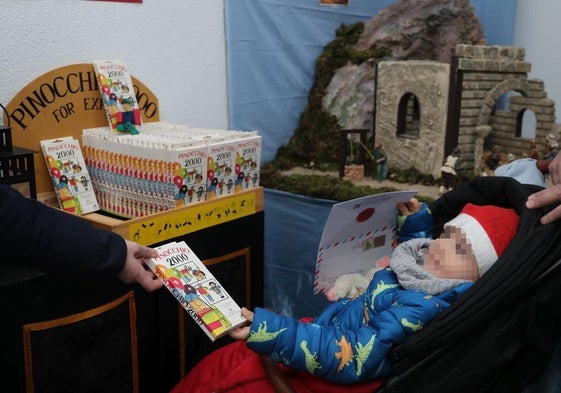 Una familia muestra a un bebé el 'Pinocho solidario' en la cofradía de la Vera Cruz.