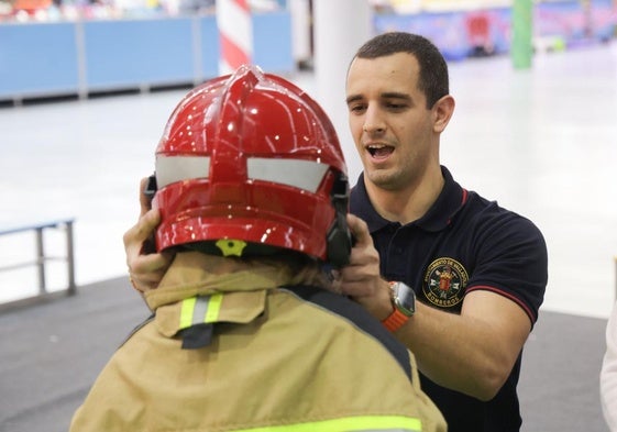 Un bombero ayuda a un niño a colocarse el casco, en una de las actividades de Navival.