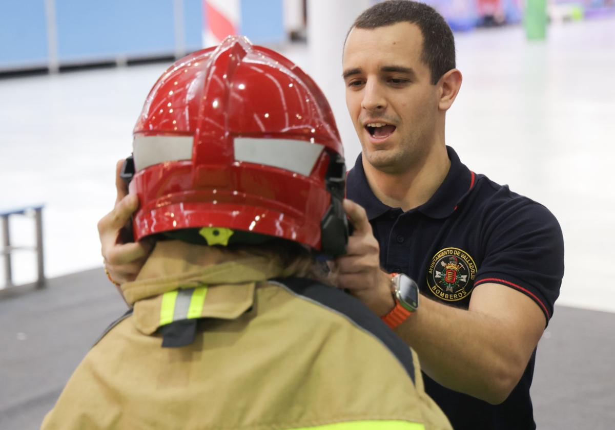 Un bombero ayuda a un niño a colocarse el casco, en una de las actividades de Navival.