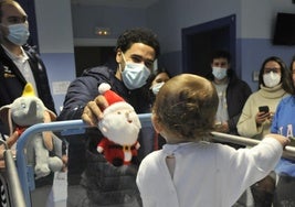 Alec Wintering entrega un peluche a un bebé en el Hospital Río Carrión.