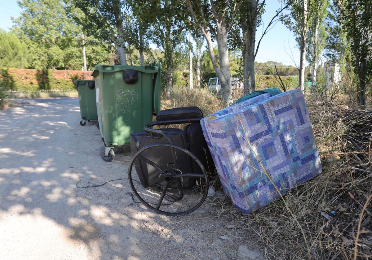 Una silla de despacho y unos colchones, junto a un contenedor.