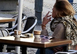 Una mujer fuma un cigarro en una terraza de un bar de Segovia.