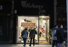 Dos mujeres miran el escaparate en liquidación de la zapatería Villalonga en los soportales de Ferrari.