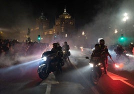 Varios moteros encaran la Acera de Recoletos entre el humo generado por las bengalas.