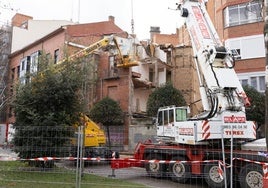 Un operario en una cesta y un gruista de apoyo trabajan en la demolición del edificio.