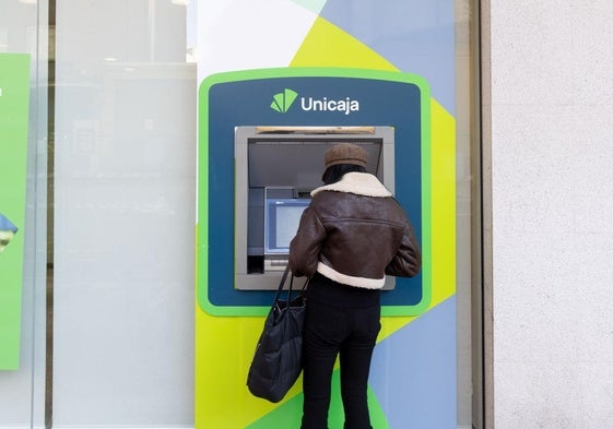 Una mujer saca dinero de un cajero de Unicaja, en una foto de archivo.