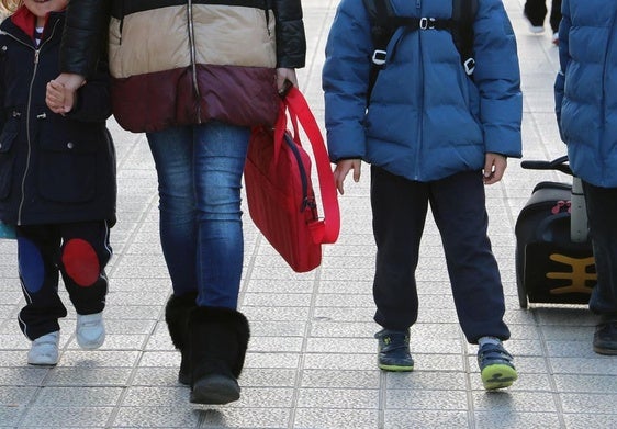 Una madres se dirige al colegio con sus tres hijos