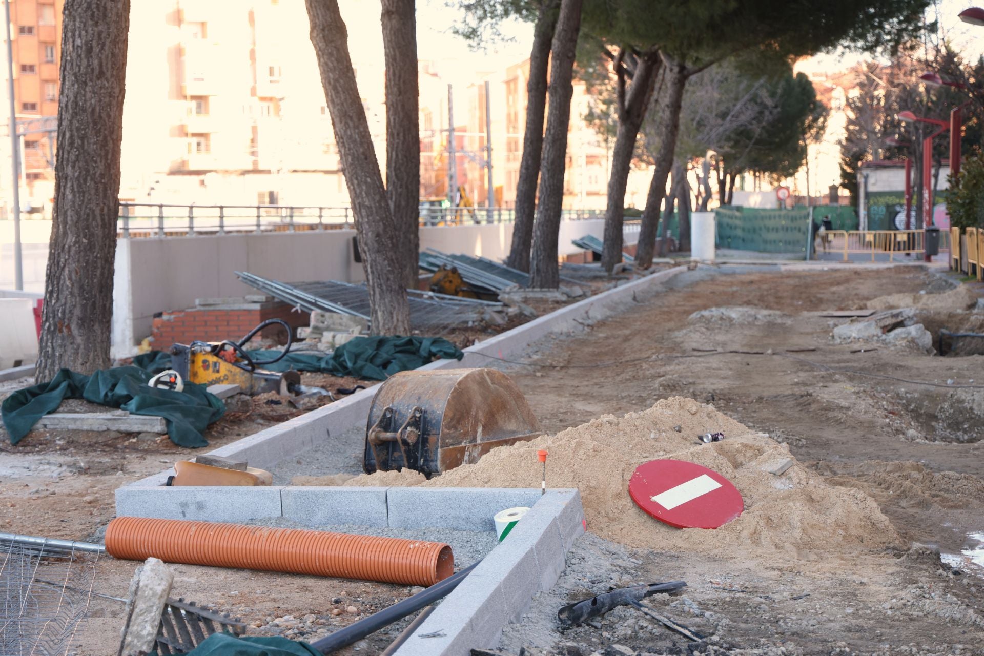 Zona de aparcamiento, delimitada por los bordillos, junto a los pinos situados junto al muro del túnel de Labradores.