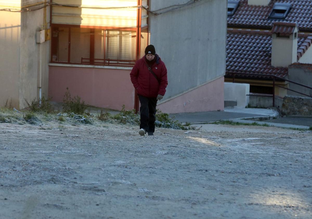 Un hombre camina por un terreno cubierto de escarcha en la ciudad de Segovia.