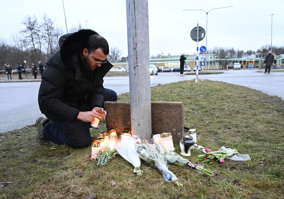 Un hombre hace una ofrenda floral a las víctimas del tiroteo en Orebro.