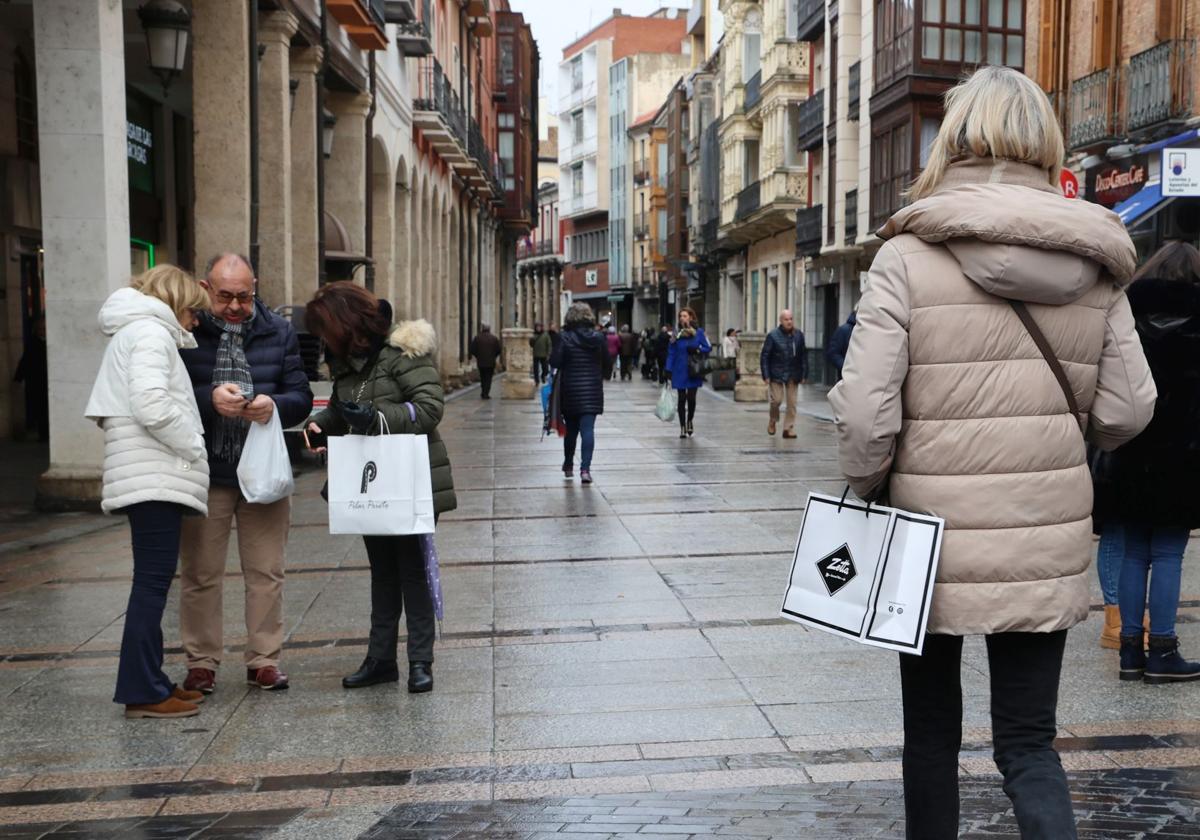 Paseantes por la Calle Mayor con bolsas de distintos establecimientos.