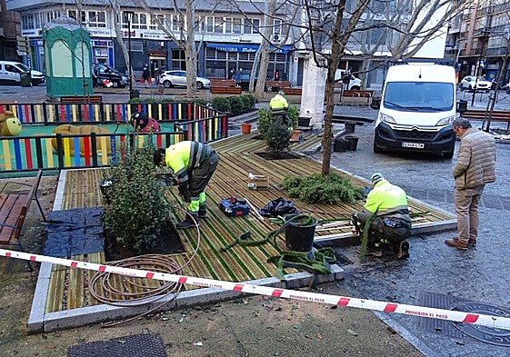 Los operarios rematan el ajardinamiento del parterre cubierto con una tarima de madera de la plaza de Caño Argales.