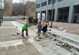 Tres niños recogen parte de la basura que dejó la afición del Sevilla en la plaza Marcos Fernández.