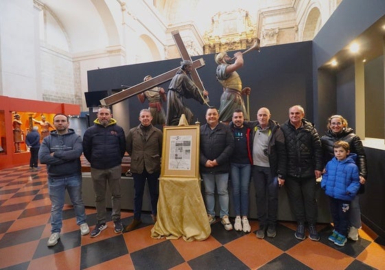 Componentes de la agrupación musical y de la directiva de la hermandad junto al cartel delante del paso del Nazareno de Santiago