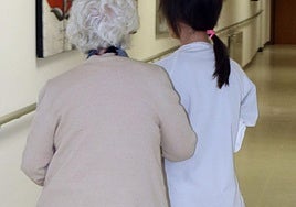 Una enfermera acompaña a una residente en un centro asistencial para la tercera edad.