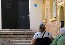 Dos mujeres, frente a la fachada de una vivienda de uso turístico.