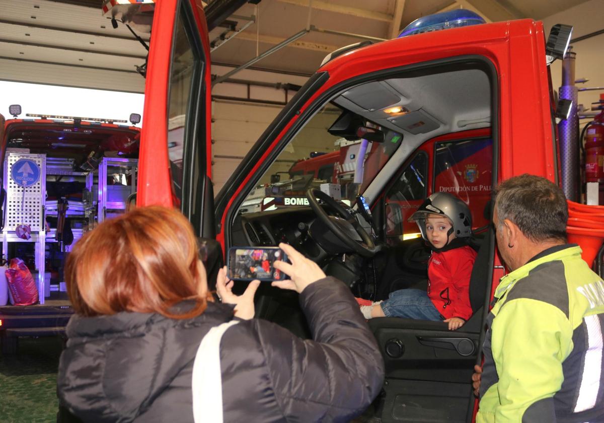 Una mujer toma una foto a un niño montado en un camión de bomberos de Baltanás.