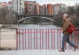 Un hombre camina por el puente de Poniente, sobre el río Pisuerga.